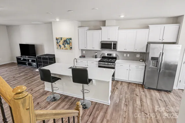 a kitchen with stainless steel appliances wooden floor and a refrigerator