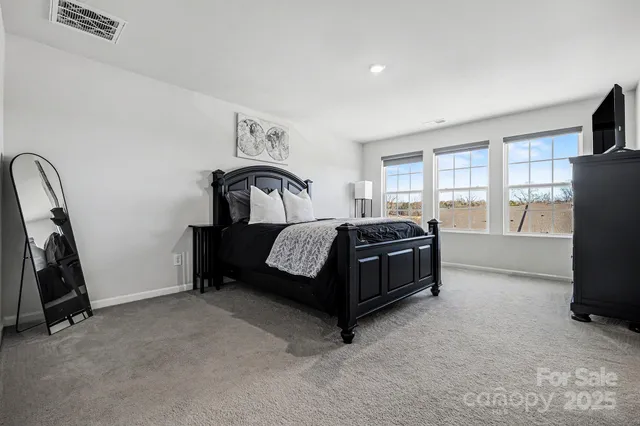 a bedroom with bed a flat tv screen and a dresser
