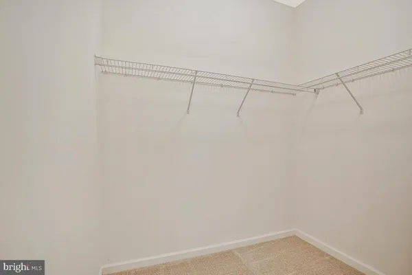 a view of an empty room with wooden floor fireplace and a window