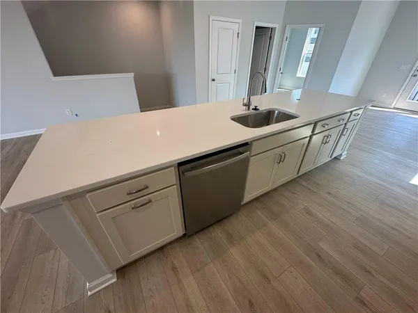 a view of kitchen and hall with wooden floor and a fireplace