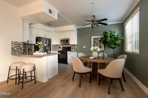 a kitchen with stainless steel appliances a dining table chairs microwave and sink