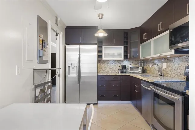 a kitchen with stainless steel appliances granite countertop a refrigerator a sink a stove and cabinets