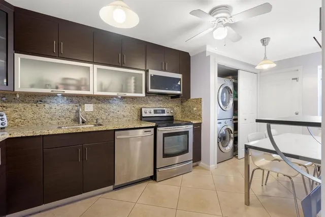 a kitchen with stainless steel appliances granite countertop a stove top oven a sink a counter space and cabinets