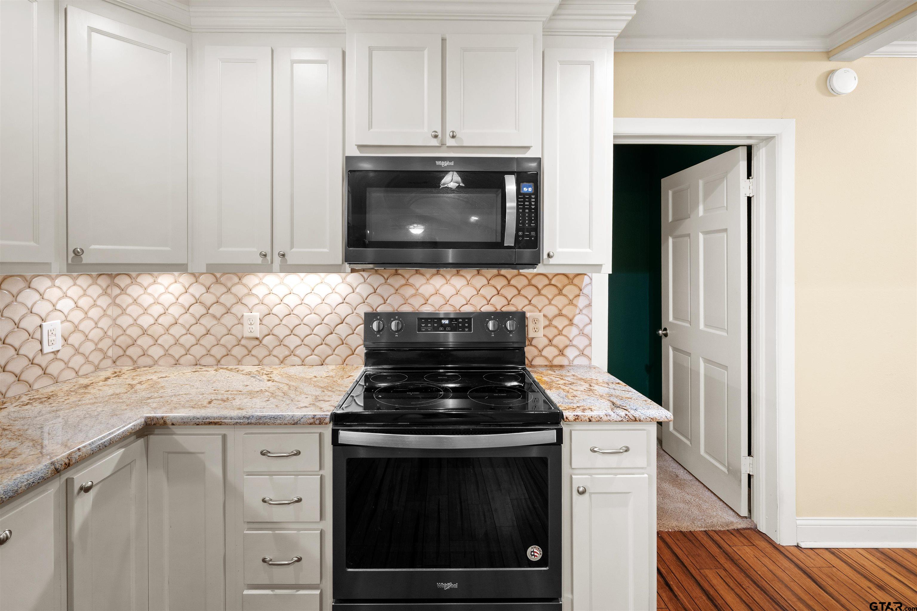 711 South Prairieville Street Athens, TX 75751 - Photo 9 of 27 a kitchen with granite countertop white cabinets and stainless steel appliances