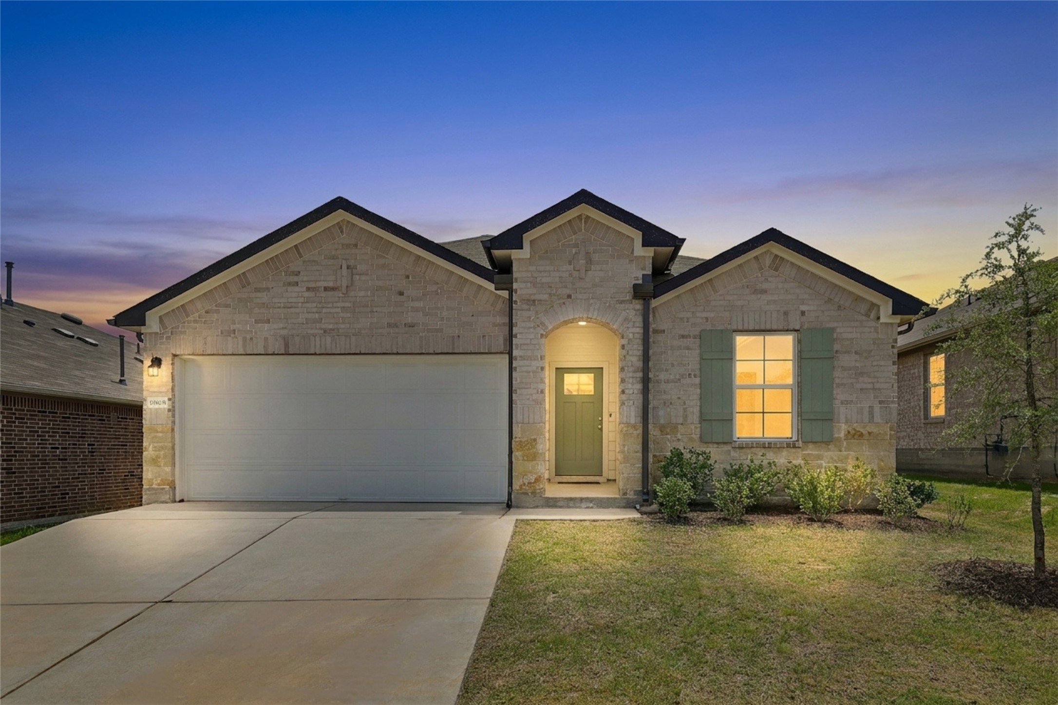 19805 Abigail Fillmore Road Manor, TX 78653 - Photo 1 of 40 A charming single-story residence with a brick facade and inviting entryway, illuminated by the twilight glow.