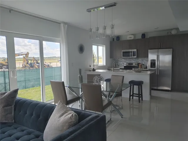 a view of a dining room with furniture a kitchen and chandelier