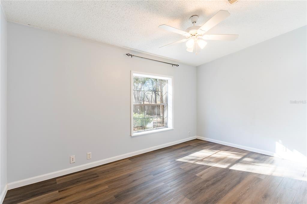 16314 Tiger Trail Spring Hill, FL 34610 - Photo 34 of 43 an empty room with wooden floor chandelier fan and windows