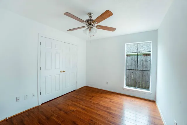 an empty room with wooden floor closet and windows