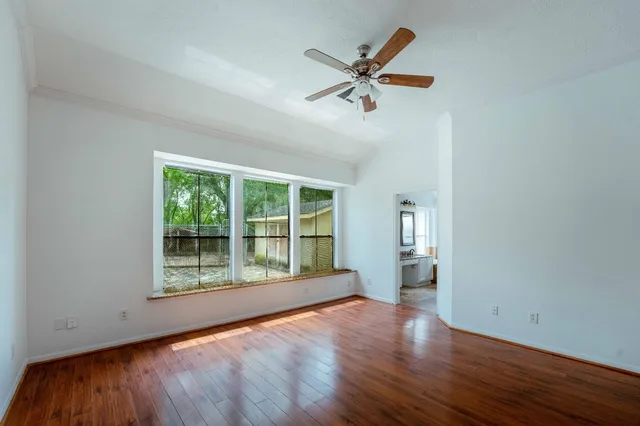 a view of an empty room with a window and wooden floor