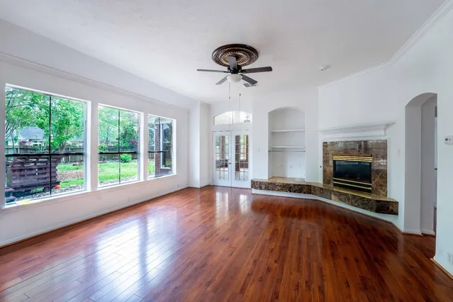 a view of an empty room with wooden floor and a window