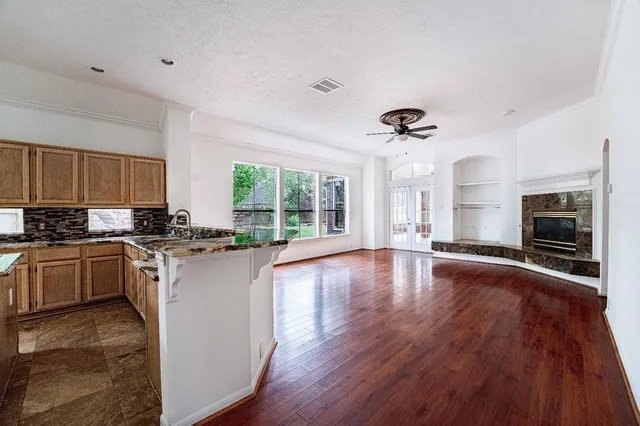 a large kitchen with hardwood floor a large window and stainless steel appliances