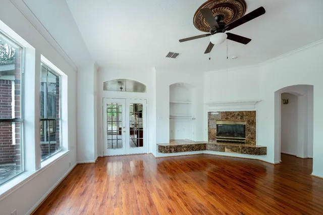 a view of an empty room with wooden floor and a window