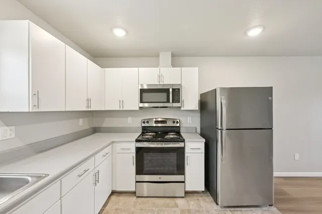 a kitchen with a refrigerator stove and white cabinets