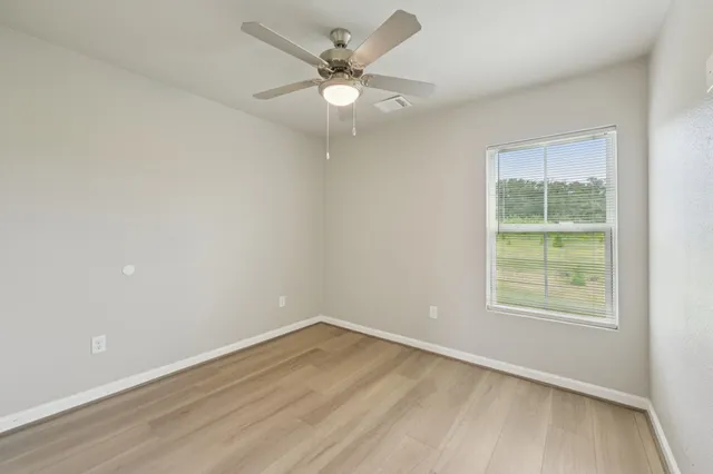 an empty room with a window and a fan