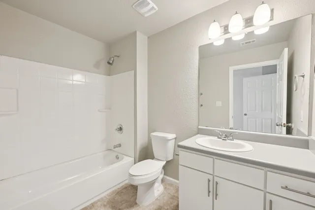 a bathroom with a toilet a sink a mirror a bathtub and shower