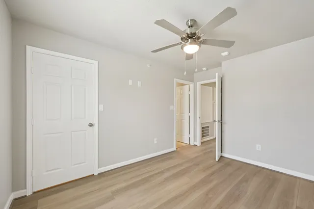 an empty room with wooden floor ceiling fan and window