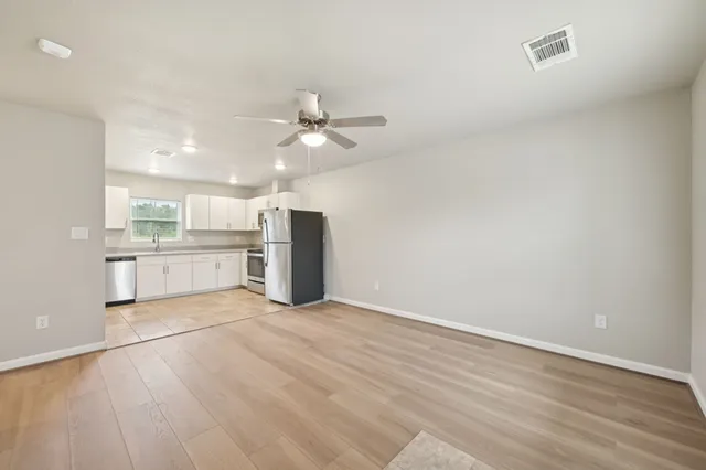 an empty room with wooden floor ceiling fan and windows