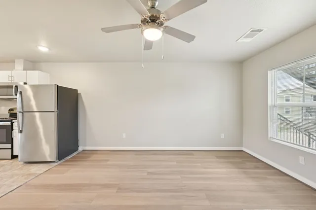 a view of empty room with wooden floor and fan