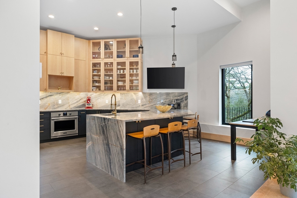 71 Grove Street Brookline, MA 02467 - Photo 18 of 42 a kitchen with stainless steel appliances granite countertop a stove top oven a sink a dining table and chairs with wooden floor