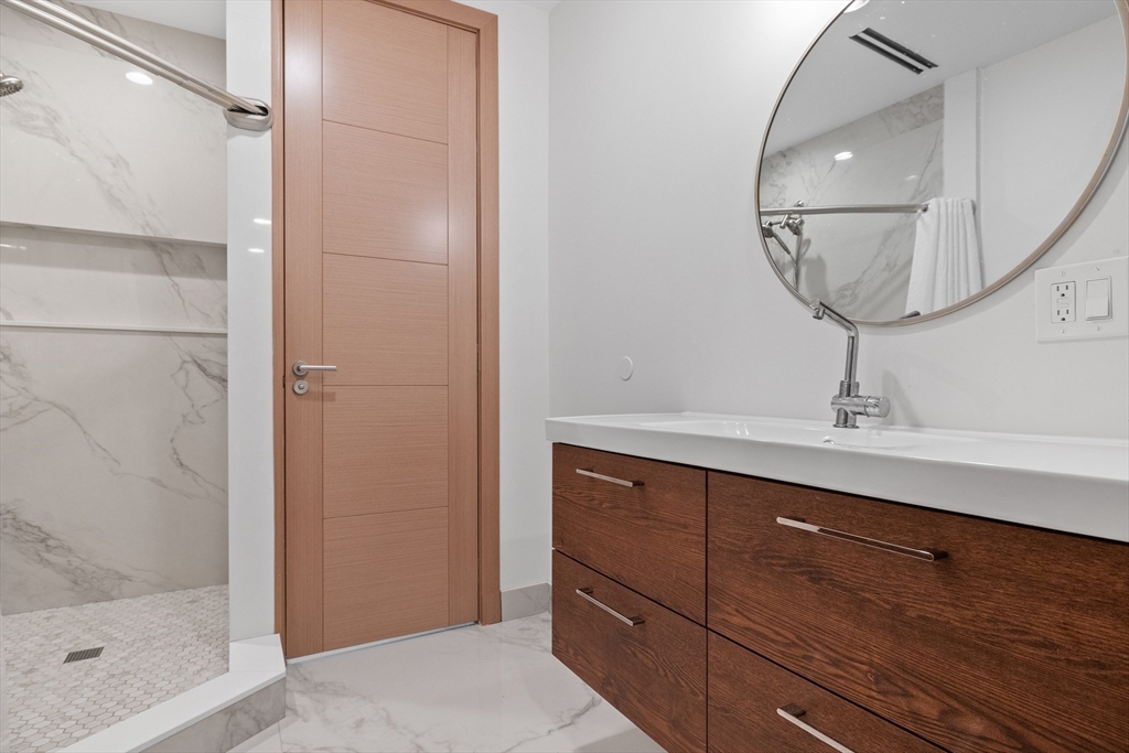 71 Grove Street Brookline, MA 02467 - Photo 32 of 42 a bathroom with a sink a mirror and shower