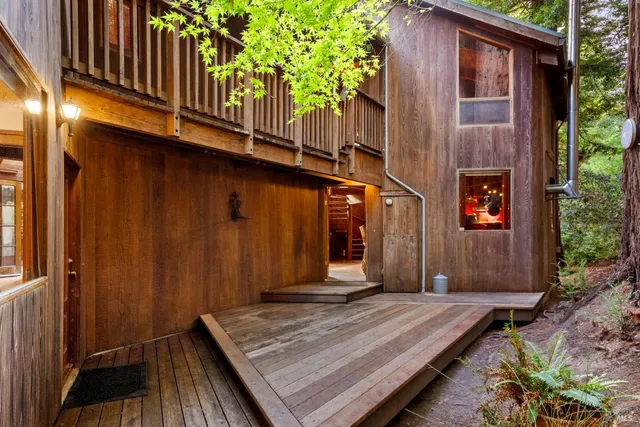 a view of a backyard with plants and large trees with wooden fence