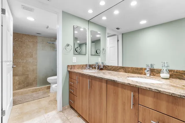 a bathroom with a granite countertop sink mirror and toilet