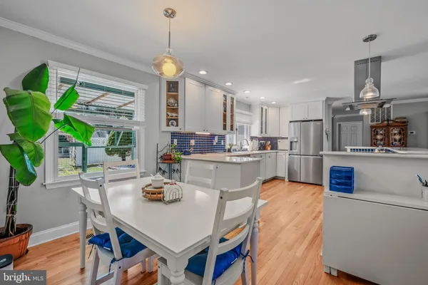 a kitchen with stainless steel appliances granite countertop a refrigerator a sink dishwasher a dining table and chairs with wooden floor