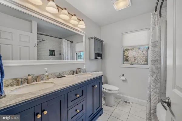 a spacious bathroom with a granite countertop double vanity sink a mirror and a toilet