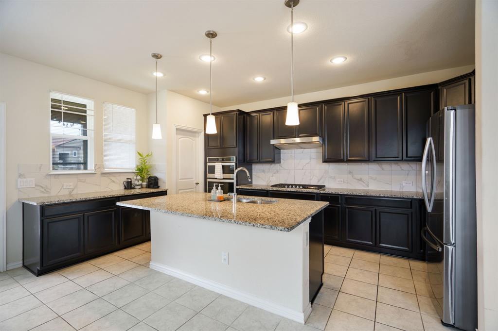 a large kitchen with granite countertop a sink and cabinets