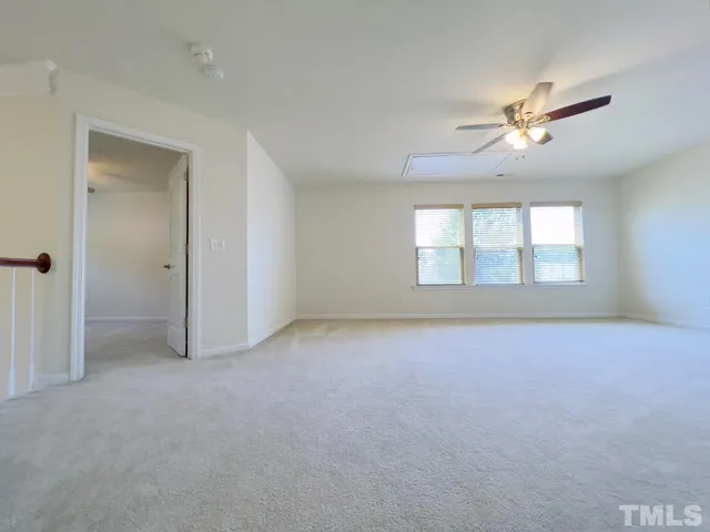 an empty room with chandelier fan and windows
