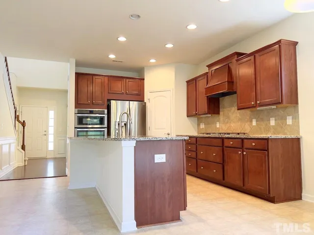 a kitchen with stainless steel appliances granite countertop a refrigerator and wooden cabinets