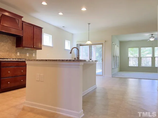 a large kitchen with granite countertop a refrigerator a sink dishwasher a stove and a wooden floors