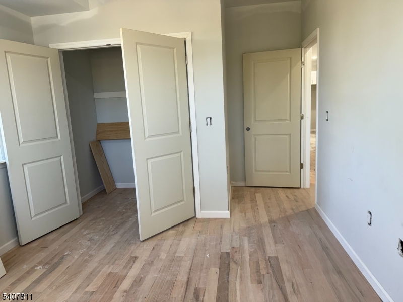 357 South 11th Street, Unit 3 Newark, NJ 07103 - Photo 4 of 13 an empty room with wooden floor and closet