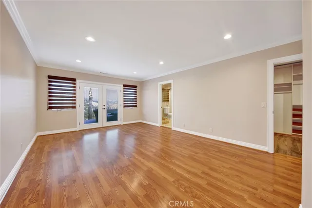 a view of empty room with wooden floor and fan