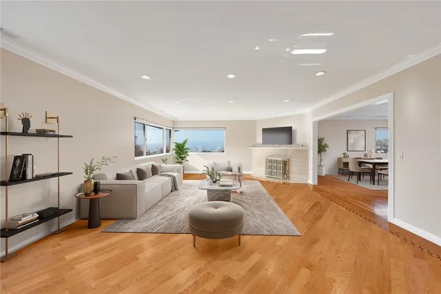 a living room with furniture a rug kitchen view and a large window