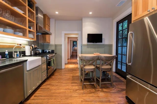 a kitchen with stainless steel appliances granite countertop a stove top oven a sink a dining table and chairs