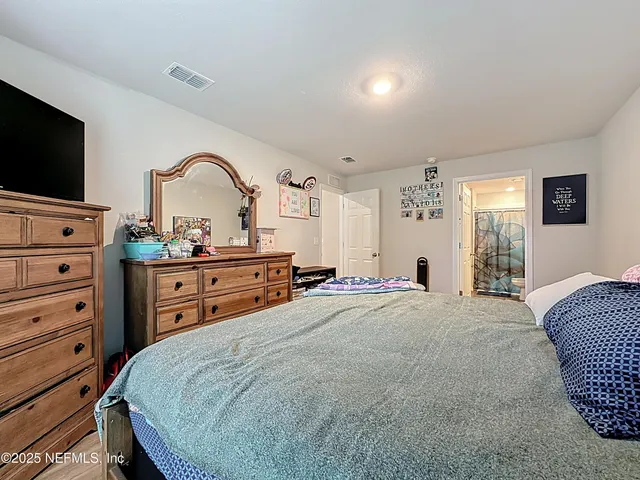 a spacious bedroom with a bed and a flat screen tv