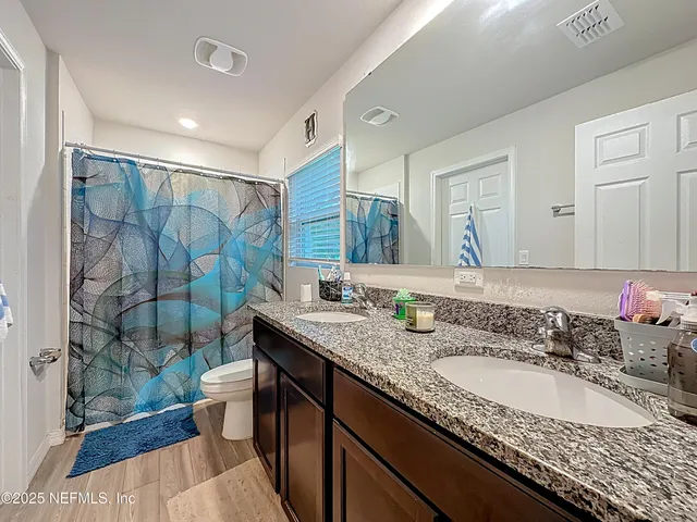 a bathroom with a granite countertop sink a toilet a mirror and shower