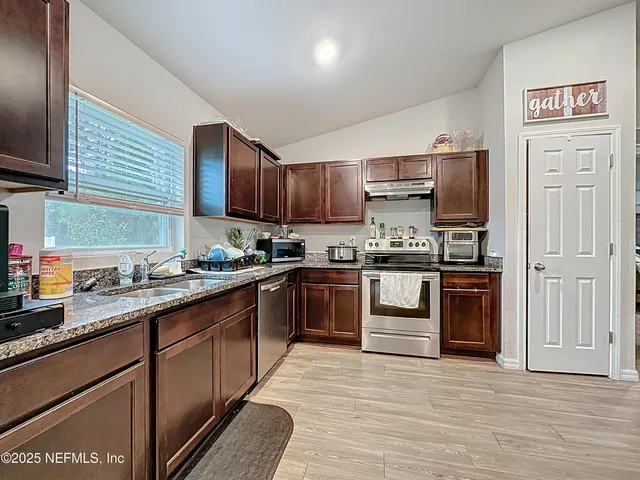 a kitchen with granite countertop wooden cabinets and a stove