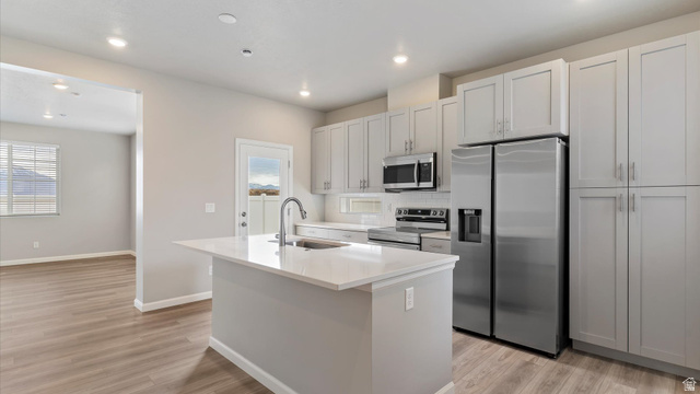 82 Provo River Road, Unit 251 Saratoga Springs, UT 84045 - Photo 10 of 32 Modern kitchen featuring light gray cabinetry, stainless steel appliances, a center island with sink, and wood-finish flooring