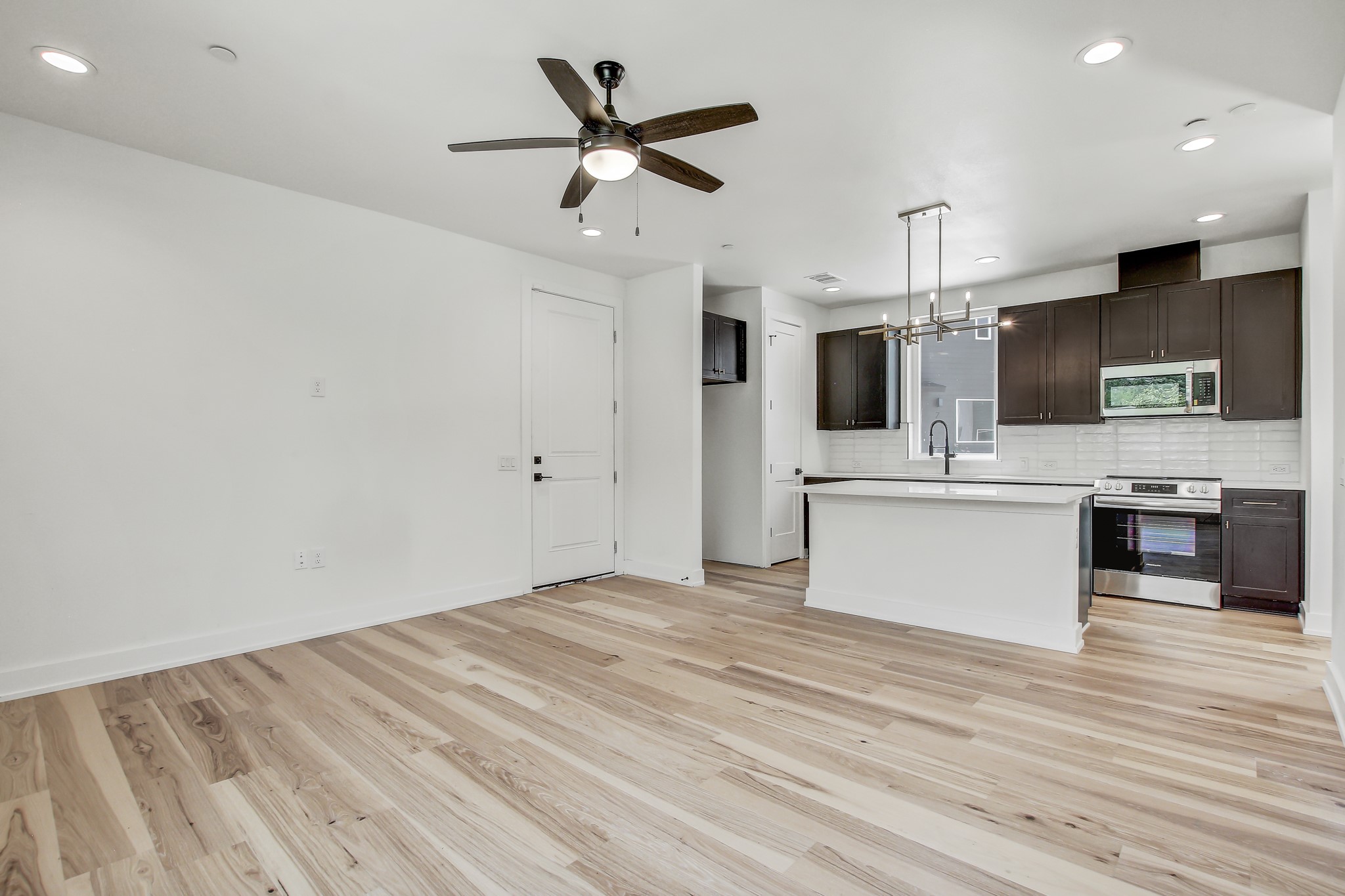 4127 East 12th Street, Unit 4 Austin, TX 78721 - Photo 1 of 32 Kitchen featuring appliances with stainless steel finishes, backsplash, light countertops, light wood-style flooring, and dark brown cabinetry