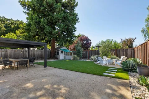 a view of a chair and table in backyard of the house