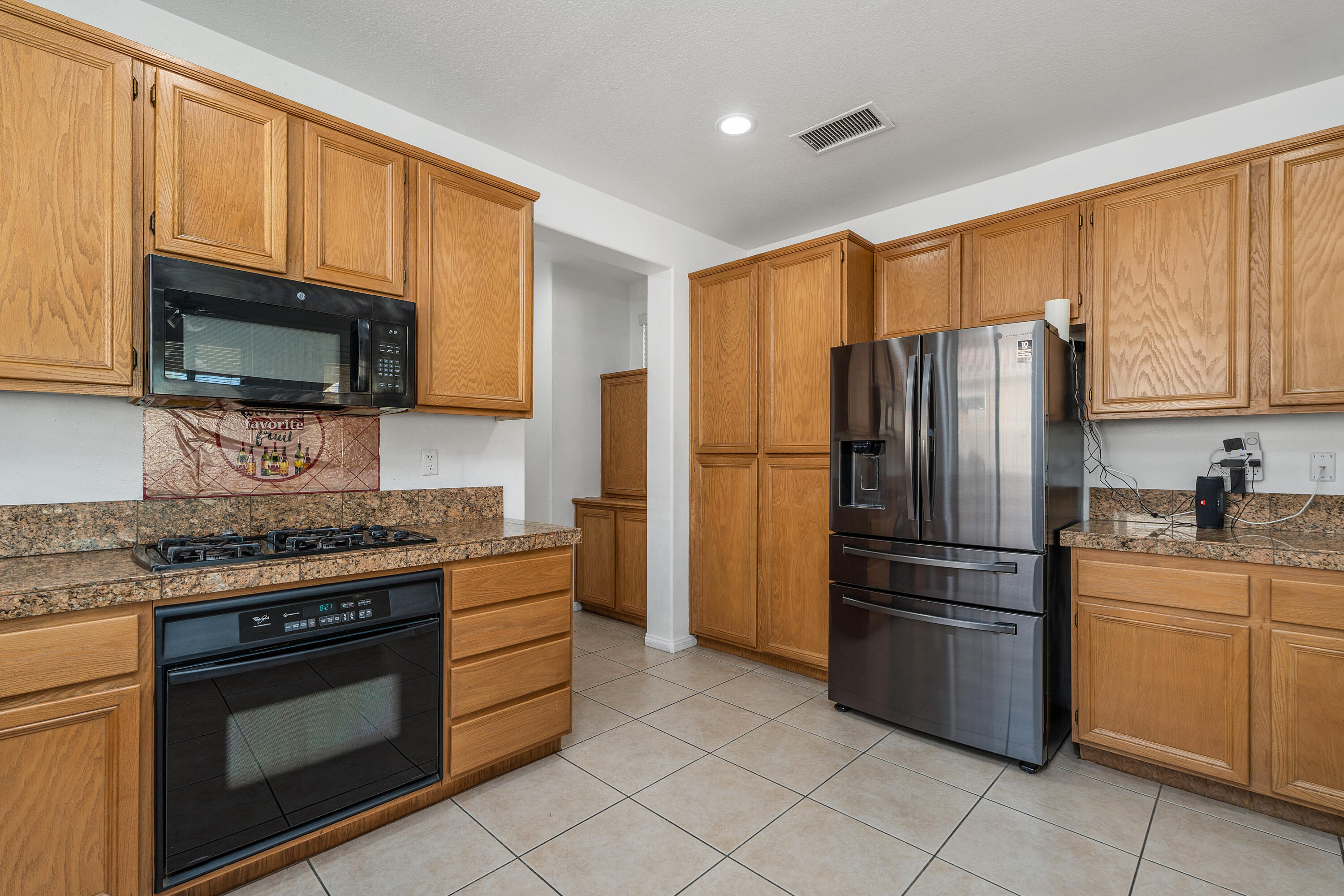 83814 Wolf Creek Road Indio, CA 92203 - Photo 13 of 28 a kitchen with granite countertop a refrigerator stove and microwave