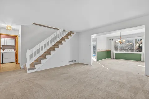 a view of an empty room with stairs and a living room