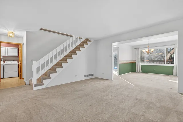 a view of an empty room with stairs and a living room