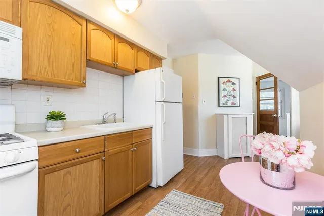 a kitchen with stainless steel appliances granite countertop a refrigerator a sink dishwasher and white cabinets with wooden floor