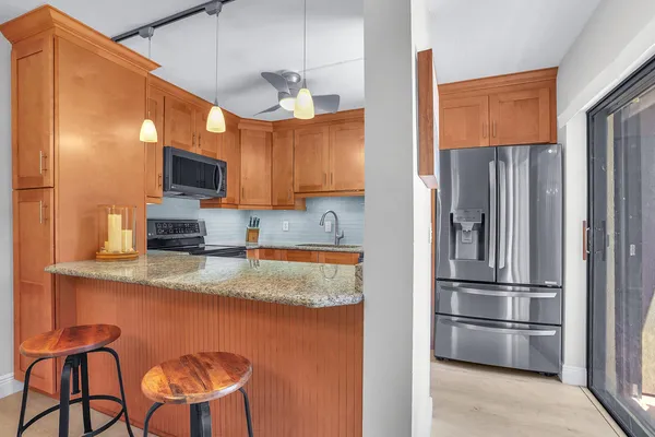 a kitchen with stainless steel appliances granite countertop a refrigerator a stove a sink and a microwave