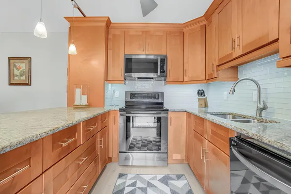 a kitchen with stainless steel appliances granite countertop a sink stove and microwave