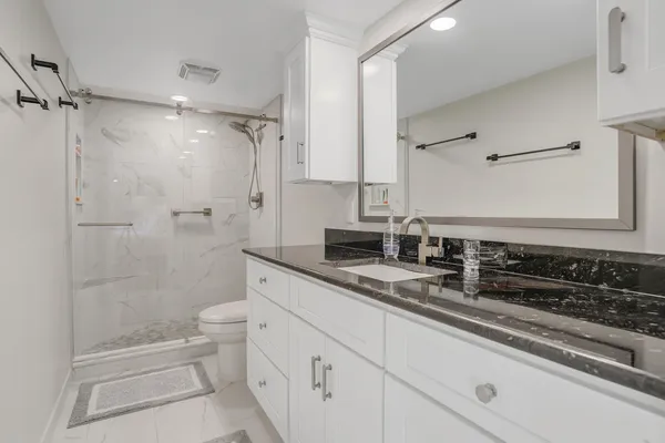 a bath room with a toilet a sink and a shower
