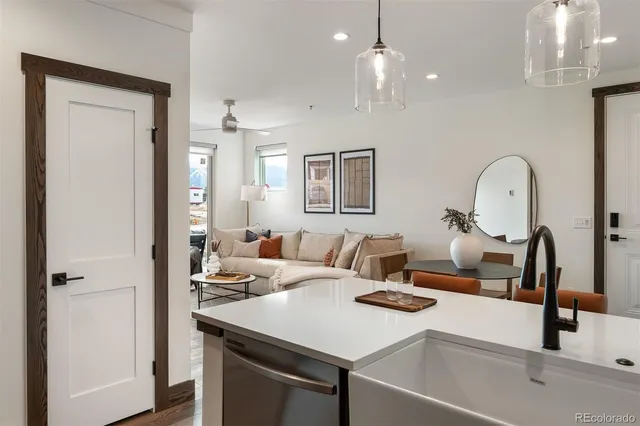a kitchen with a sink dishwasher a dining table and chairs with wooden floor